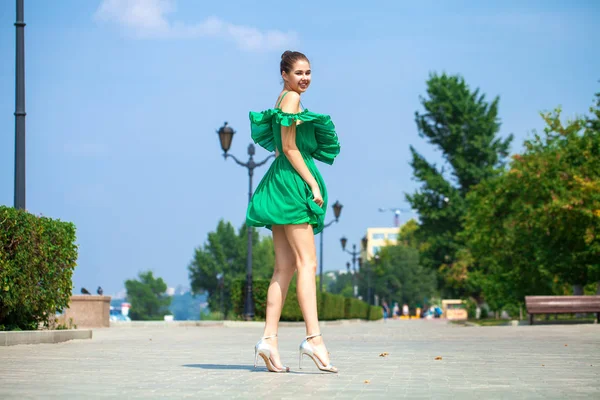 Jeune belle femme en robe verte marchant sur le stree d'été — Photo