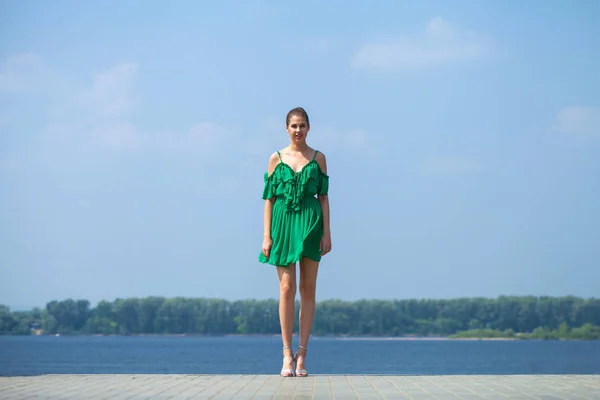 Jovem linda menina morena em vestido verde caminha ao longo do emb — Fotografia de Stock