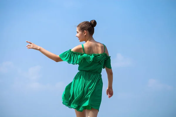 Young beautiful brunette girl in green dress walks along the emb — Stock Photo, Image