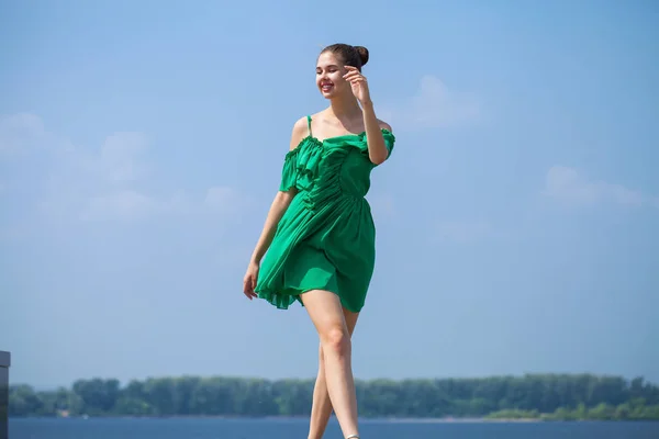 Jeune belle femme en robe verte marchant sur le stree d'été — Photo