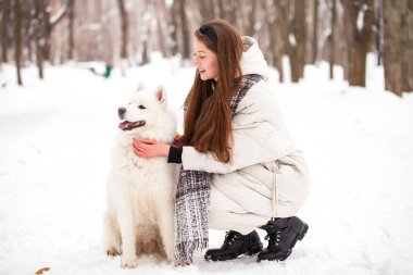 Köpeği olan güzel bir kadın kış parkında yürüyor.