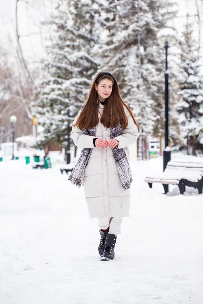 若いですブルネット女性でホワイトダウンジャケットで冬の通り — ストック写真