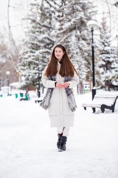 Молодая брюнетка в белой куртке на зимней улице — стоковое фото