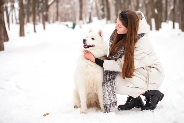 Giovane bella donna con un cane passeggia in un parco invernale — Foto Stock