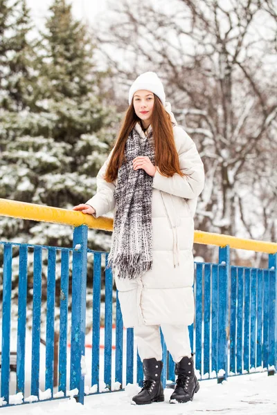 Young brunette woman in white down jacket in winter street — 스톡 사진