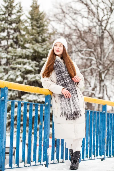 Jonge brunette vrouw in wit donsjas in de winter straat — Stockfoto