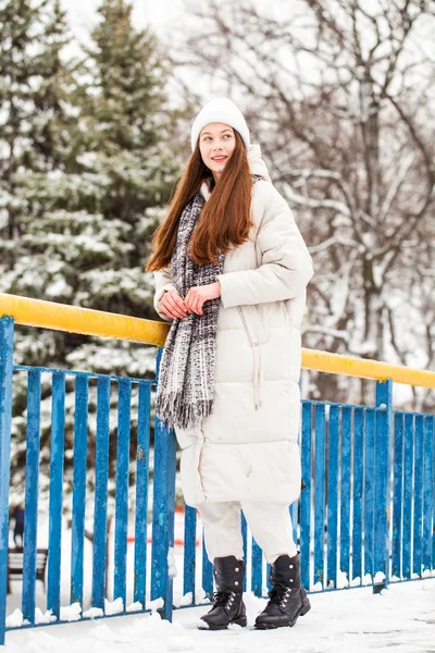Jonge brunette vrouw in wit donsjas in de winter straat — Stockfoto