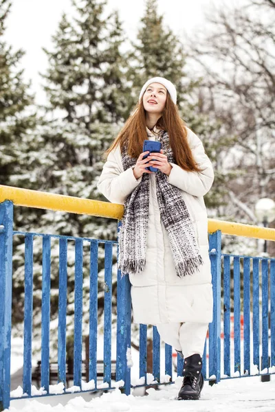 Молодая брюнетка в белой куртке на зимней улице — стоковое фото