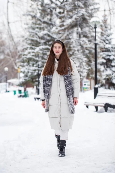 若いですブルネット女性でホワイトダウンジャケットで冬の通り — ストック写真