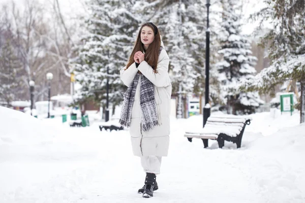 Young brunette woman in white down jacket in winter street — 스톡 사진