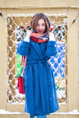 Mavi ceketli mutlu genç kız kış sokağında poz veriyor.