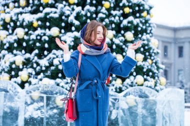 Mavi ceketli mutlu genç kız kış sokağında poz veriyor.