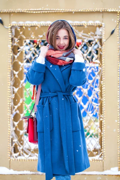 Szczęśliwa młoda dziewczyna w niebieskim płaszczu pozowanie w zimowej ulicy — Zdjęcie stockowe