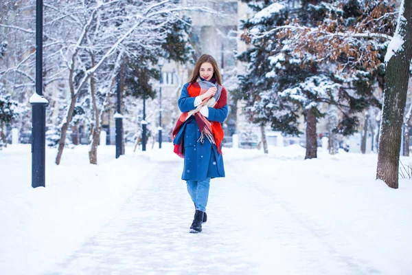 Счастливая молодая девушка в синем пальто позирует на зимней улице — стоковое фото