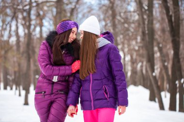 İki mutlu güzel kız arkadaş kışın şehir merkezinde yürür.