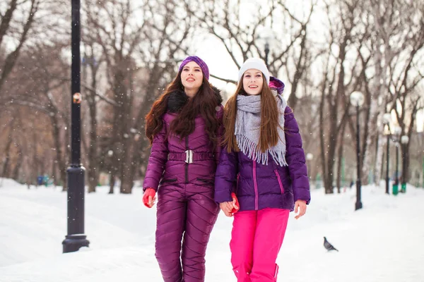 Two happy beautiful girlfriends walk in the winter in a city par — Stock Photo, Image