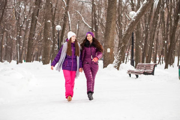 Две счастливые красивые девушки гуляют зимой в городе пар — стоковое фото