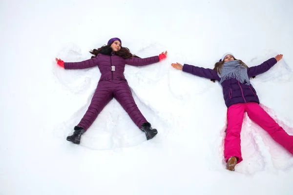 雪の天使二人の若いです美しいです女の子でスキースーツの上にある — ストック写真