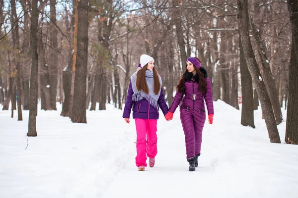 Twee gelukkige mooie vriendinnen wandelen in de winter in een stad par — Stockfoto