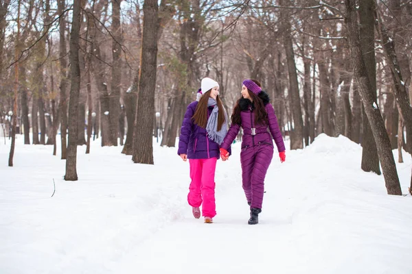 Twee gelukkige mooie vriendinnen wandelen in de winter in een stad par — Stockfoto