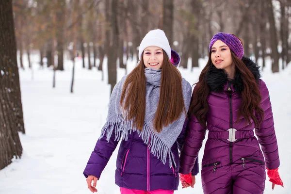 Twee gelukkige mooie vriendinnen wandelen in de winter in een stad par — Stockfoto