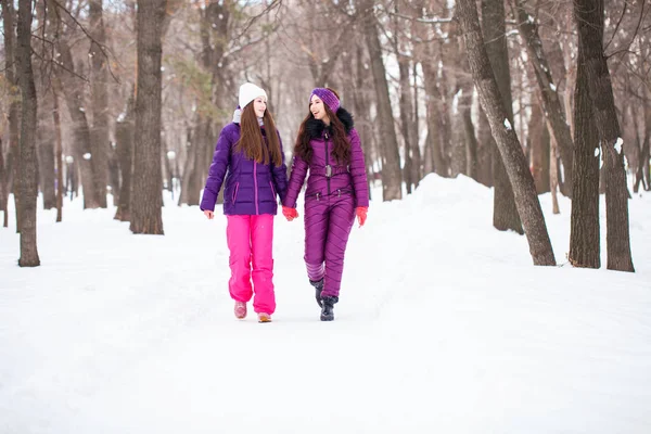 Dwie szczęśliwe piękne dziewczyny chodzić w zimie w mieście par — Zdjęcie stockowe