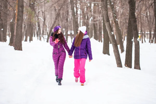 Two happy beautiful girlfriends walk in the winter in a city par — Stock Photo, Image