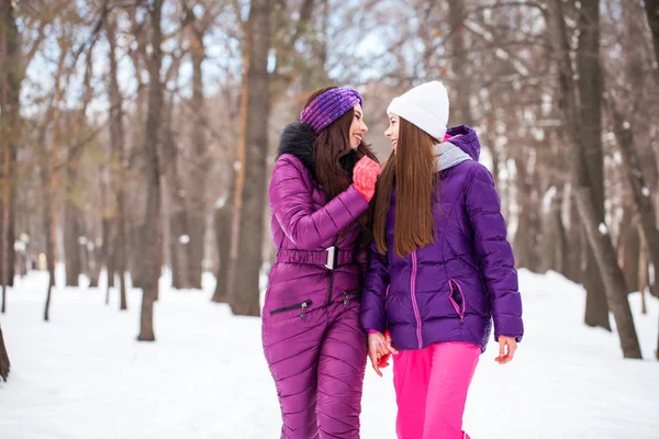 Two happy beautiful girlfriends walk in the winter in a city par — Stock Photo, Image