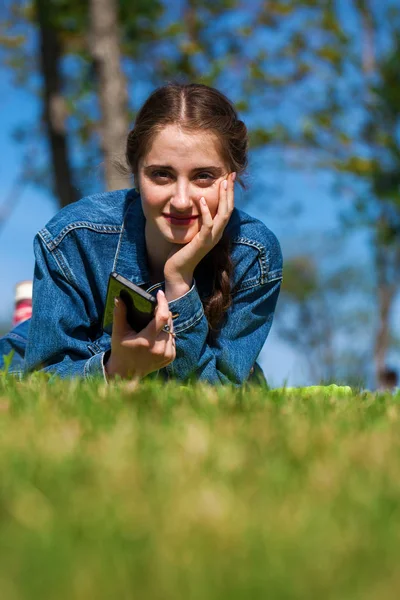 Piękna młoda brunetka kobieta leżąca na zielonej trawie — Zdjęcie stockowe