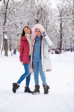Kışın parkta yürüyen iki güzel kadının portresi.