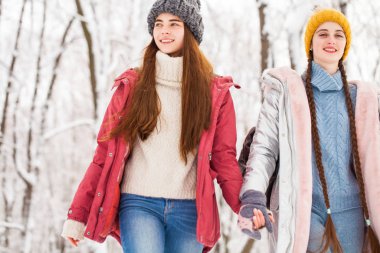 İki mutlu güzel kız arkadaş kışın şehir merkezinde yürür.