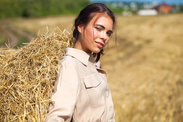 Menina bonita em um vestido bege posando em um fundo de haysta — Fotografia de Stock