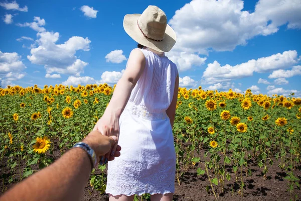 Folgen Sie mir, junge Frau hält einen Mann Hand Feld von Sonnenblumen — Stockfoto