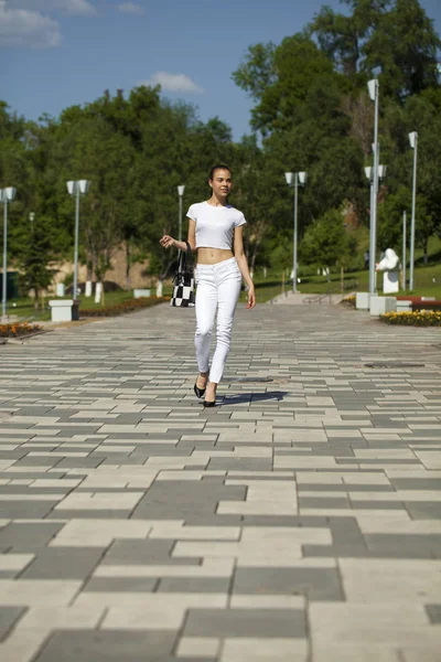 Beyaz kot pantolon ve t-shirt yürüyüş genç güzel esmer kız — Stok fotoğraf