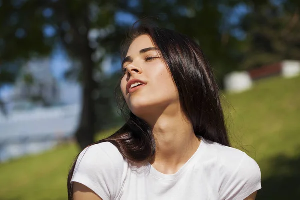 Bella donna bruna in posa contro il parco estivo, luminoso sole — Foto Stock