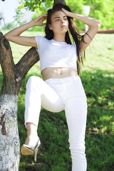 Mooie brunette vrouw poseren tegen zomerpark, heldere Sunn — Stockfoto