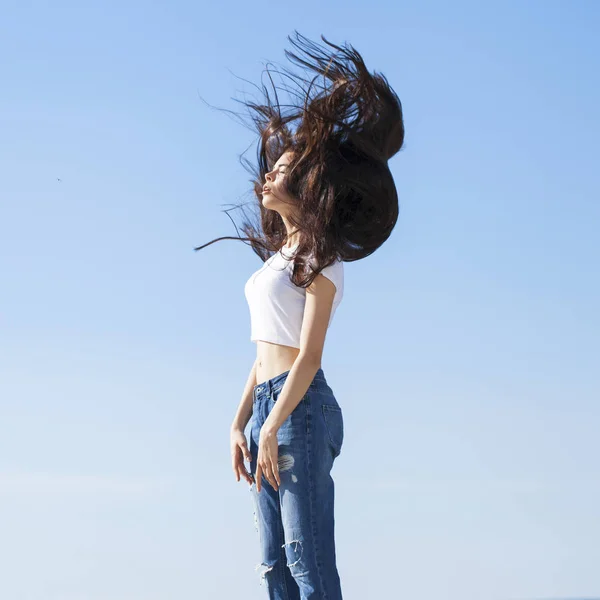 Bella donna bruna in posa contro il cielo blu luminoso soleggiato noi — Foto Stock