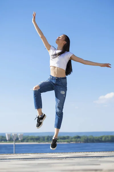 Joven hermosa morena posando contra el cielo azul brillante su — Foto de Stock