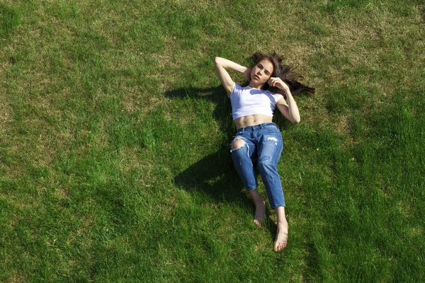 Retrato de una joven hermosa niña descansando en el césped en el pa — Foto de Stock