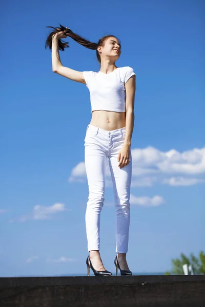 美丽的黑发女人摆姿势对蓝天明亮的阳光我们 — 图库照片