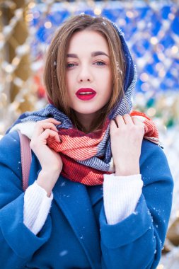 Mavi ceketli mutlu genç kız kış sokağında poz veriyor.