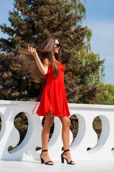 Jonge mooie vrouw in rode jurk op de zomer straat — Stockfoto