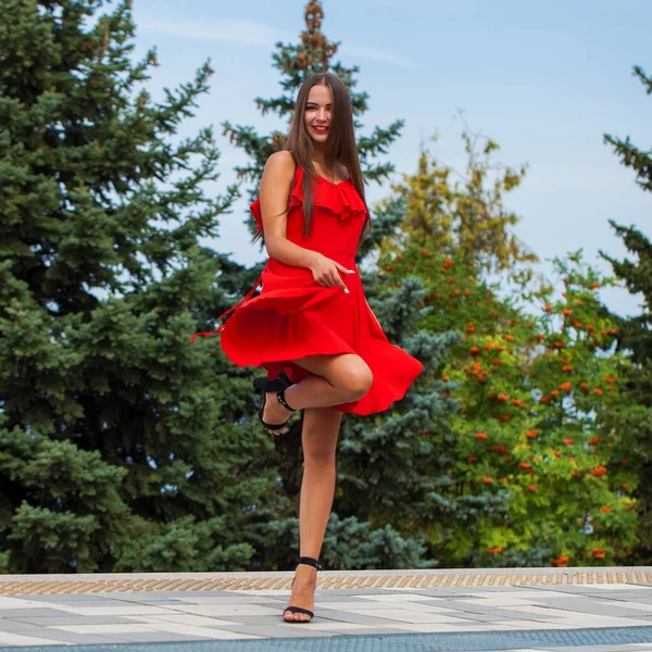 Menina bonita nova em vestido vermelho andando na rua de verão — Fotografia de Stock