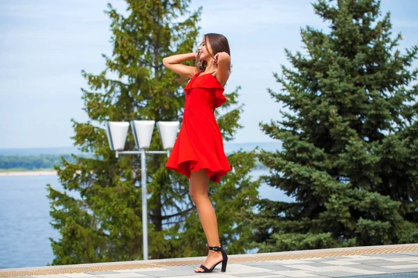 Jovem modelo bonito em vestido vermelho andando na rua de verão — Fotografia de Stock