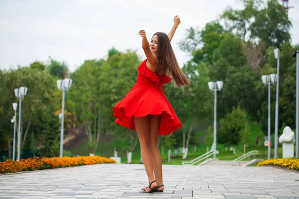 Yaz sokakta yürüyen kırmızı elbiseli genç güzel kadın — Stok fotoğraf