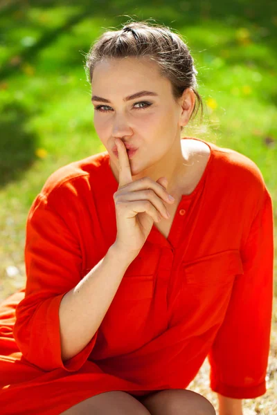 若い美しいブルネットの女性は、sig として唇に人差し指を入れています。 — ストック写真