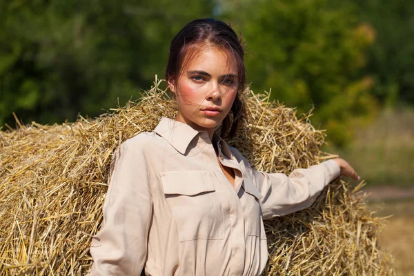 Krásná dívka v béžových šatech na pozadí haysta — Stock fotografie