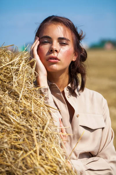 Krásná dívka v béžových šatech na pozadí haysta — Stock fotografie