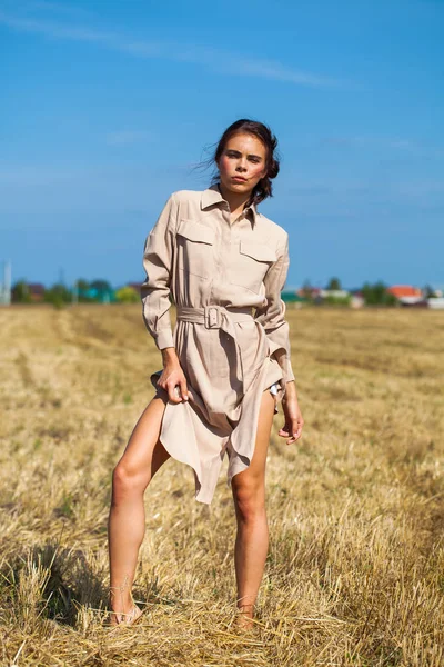 Joven modelo morena hermosa en un vestido beige posando contra t — Foto de Stock