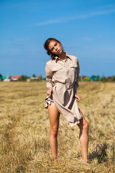 Fiatal gyönyörű barna modell egy bézs ruhában pózol ellene — Stock Fotó